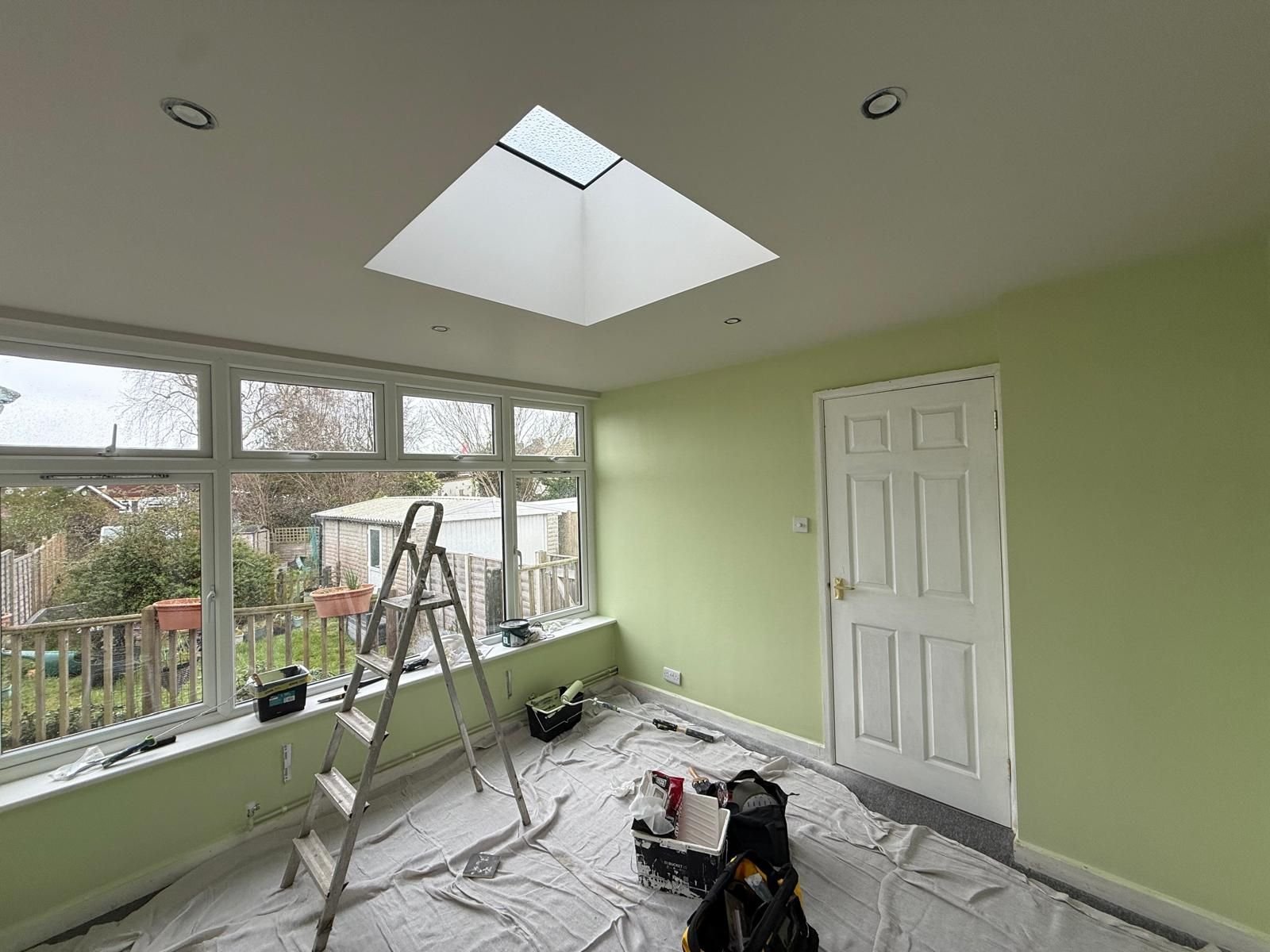 Garden room painted fresh green with floors fully dust-sheeted