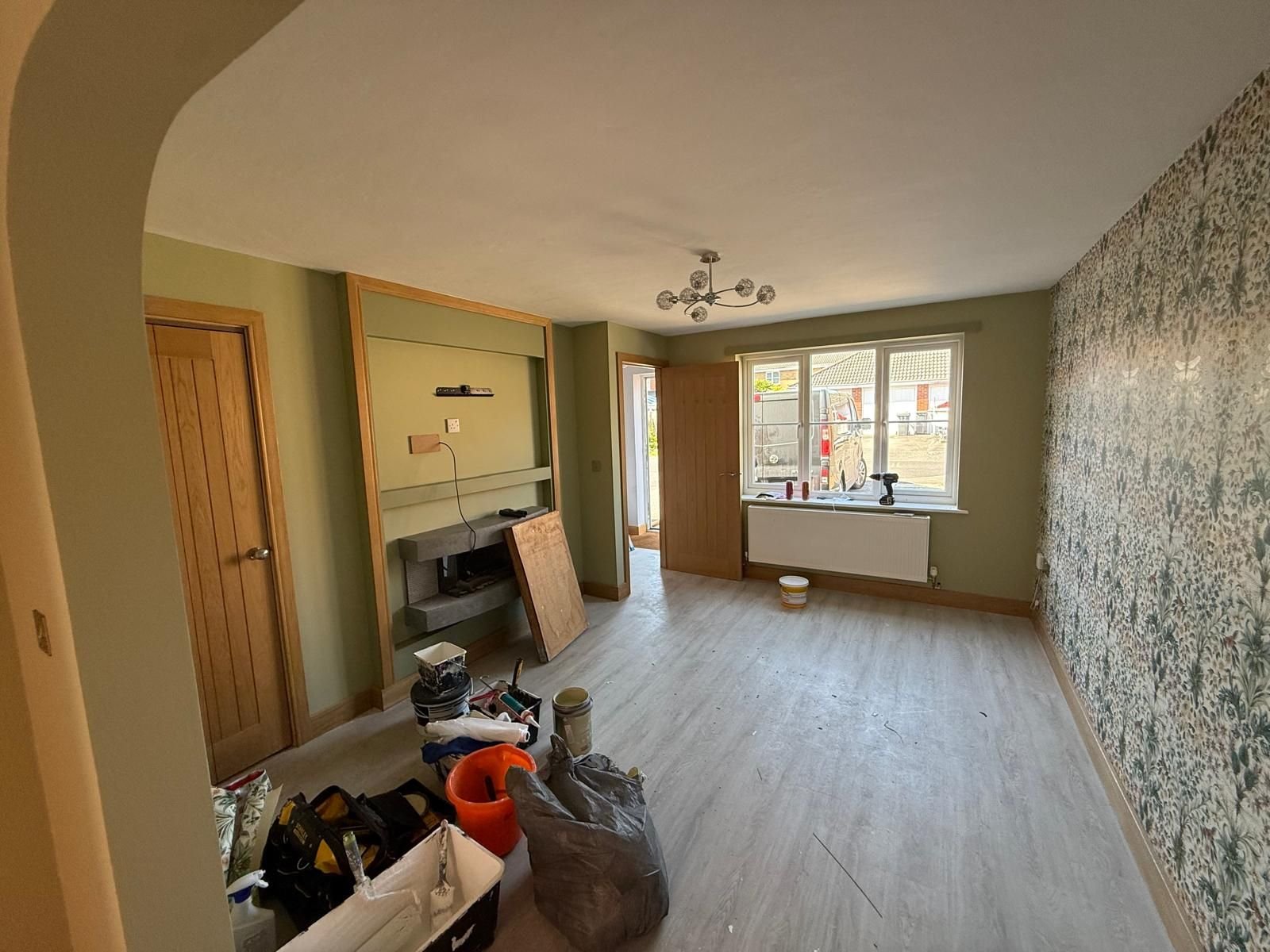 The same living room finished in sage green with floral feature wallpaper