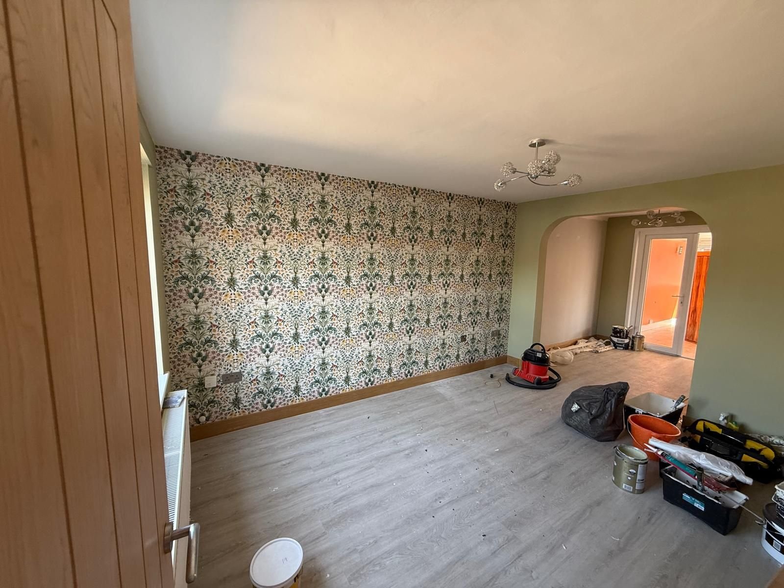 Living room decorated in sage green with botanical feature wallpaper