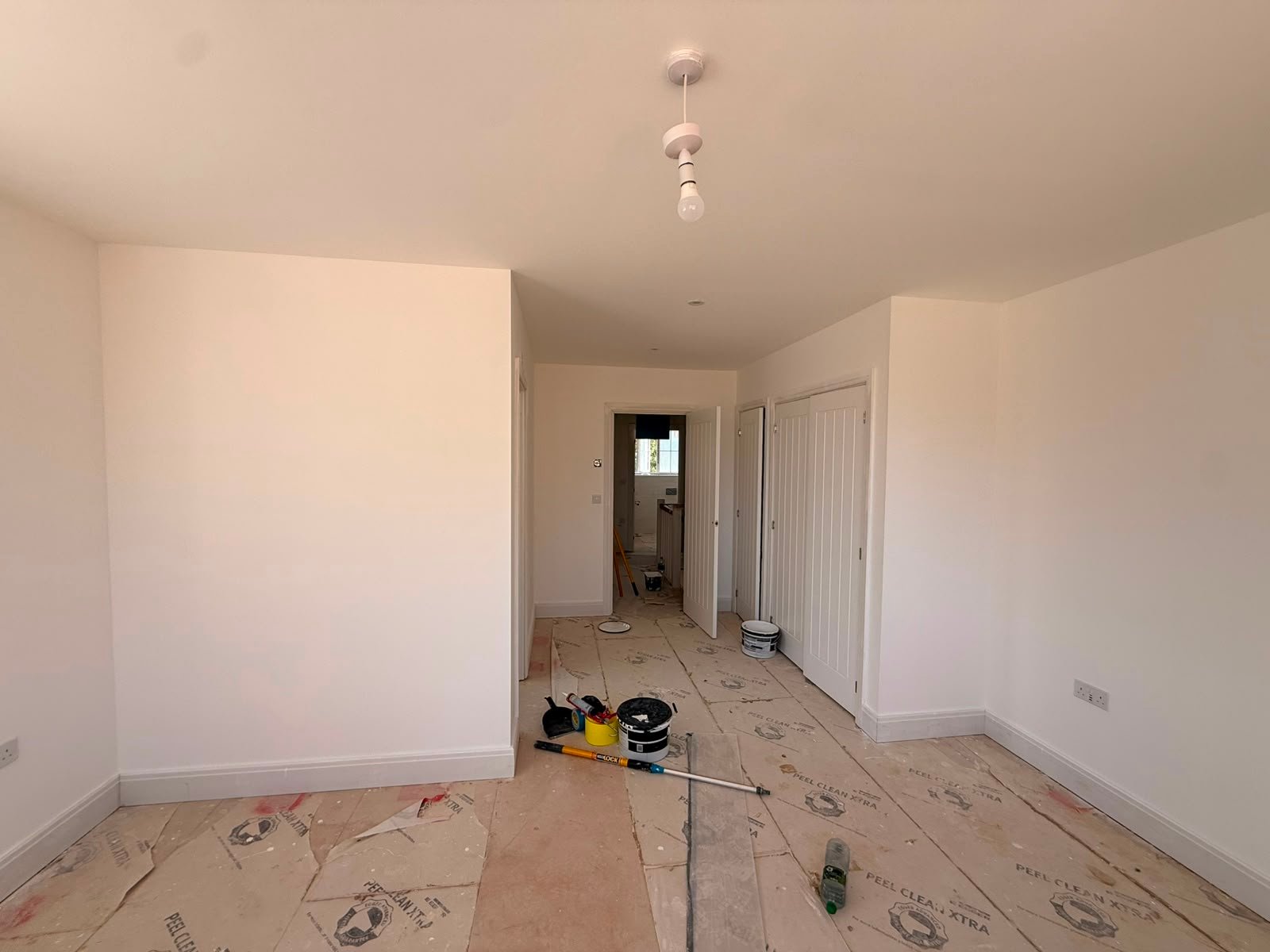 Freshly painted white walls in a new-build home with floors fully protected