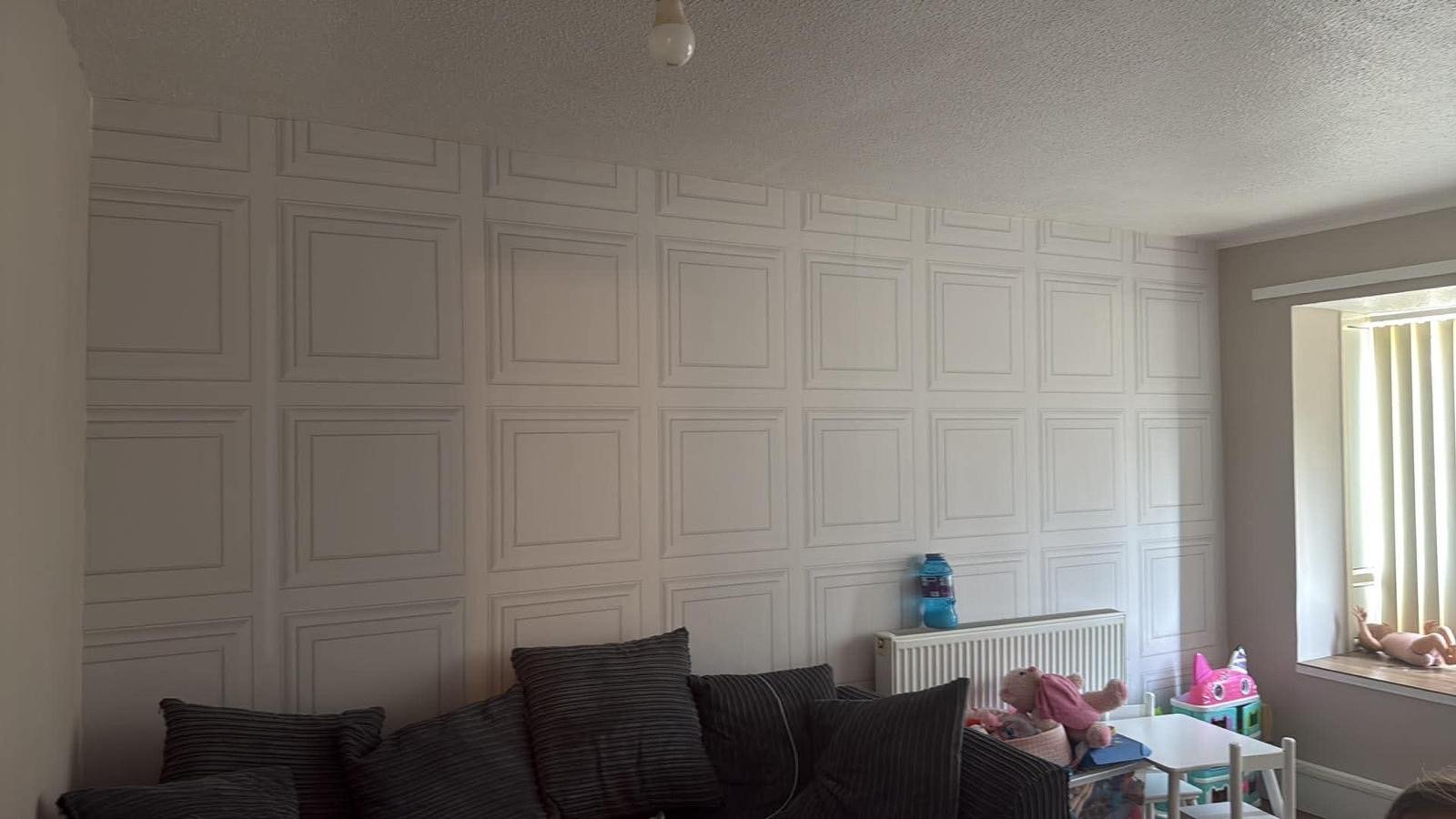 White panel-effect feature wallpaper across a living room wall